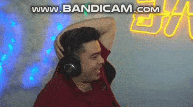 a man wearing headphones is standing in front of a neon sign that says www.bandam.com