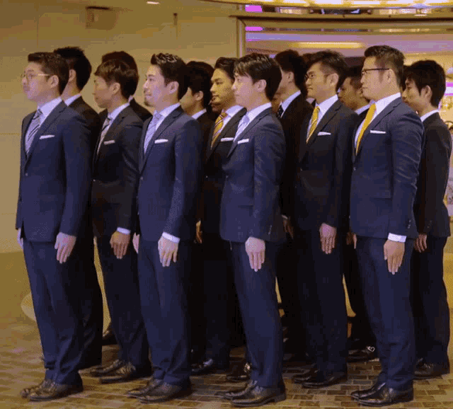 a group of men in suits are standing in a line