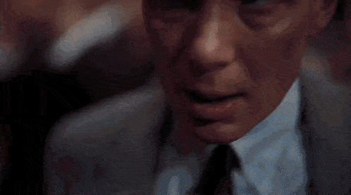 a close up of a man 's face in a suit and tie with his eyes closed .