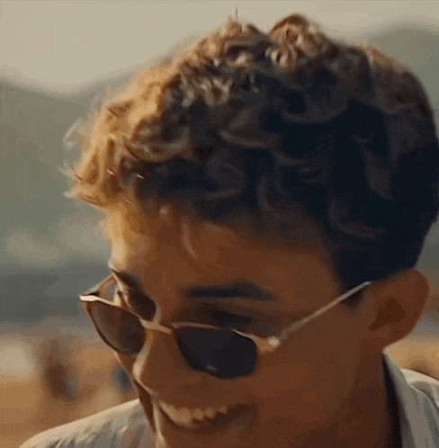 a young man wearing sunglasses is smiling and looking at the camera