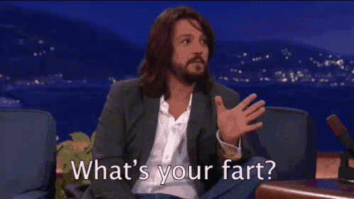 a man with long hair and a beard is sitting on a couch and asking what 's your fart