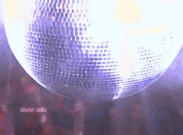 a disco ball is spinning in the air in front of a crowd of people .
