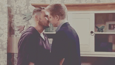 two men are kissing in a living room .