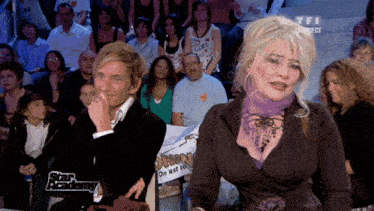 a man and a woman are sitting in front of a crowd with a sign that says star academy