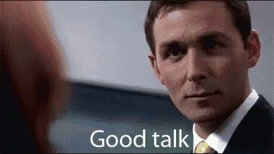 a man in a suit and tie is talking to another man and says good talk