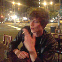 a man in a leather jacket is smoking a cigarette