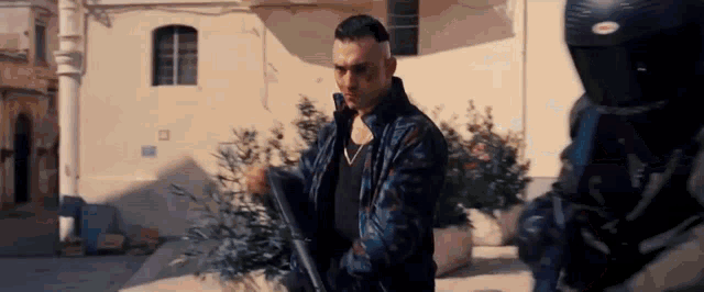 a man in a blue jacket is holding a gun in his hand .
