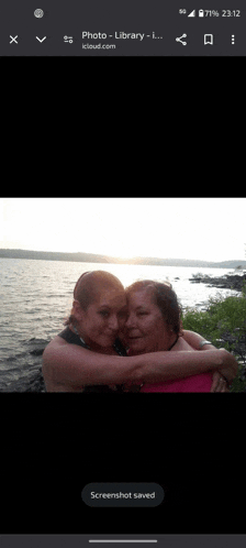 a screenshot of two women hugging each other in front of a lake ..