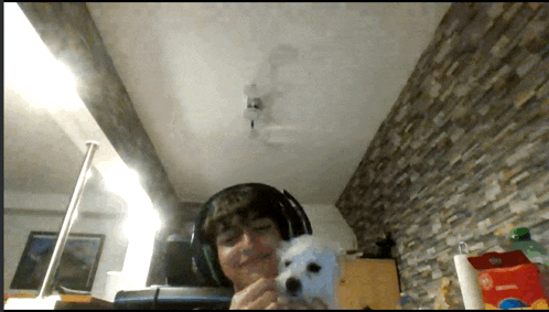 a man wearing headphones holds a white dog