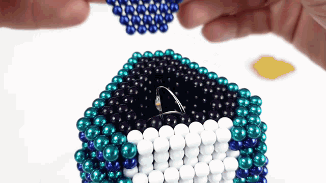 a person is holding a ring in a box made of beads