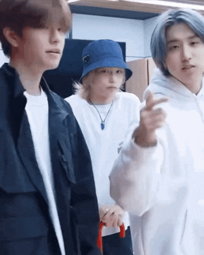 a group of young men are standing next to each other in a room and one of them is wearing a blue hat .