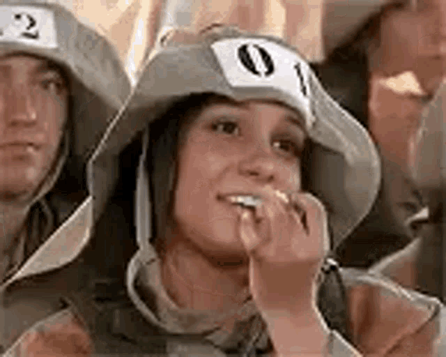 a woman wearing a hat with a number on it is sitting next to a man wearing a hat .