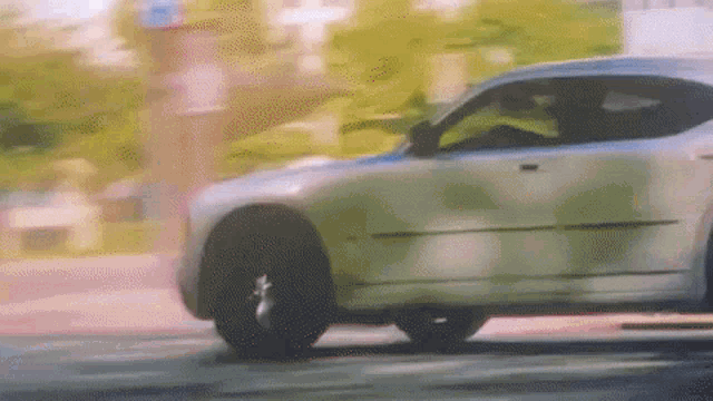 a car is driving down a street with trees in the background