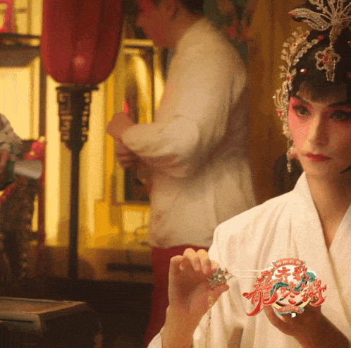 a woman in a white robe is holding a mask that says ' chinese ' on it
