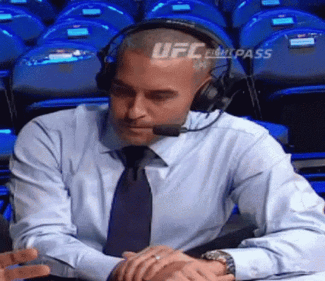 a man wearing headphones and a tie is sitting at a table with his hands folded .