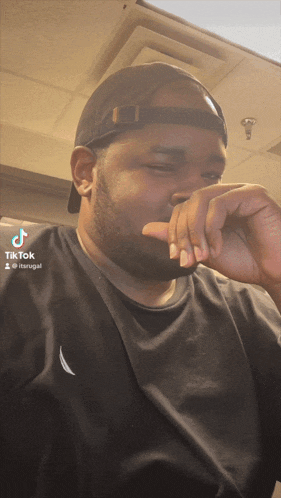 a man wearing a baseball cap and a black shirt has a tiktok icon on his face
