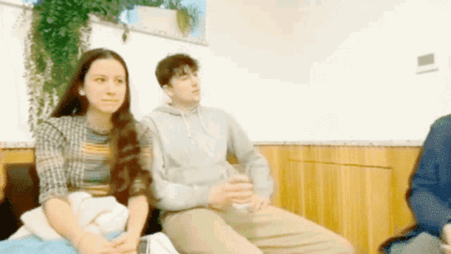 a group of people are sitting in a room and one of them is holding a glass of water