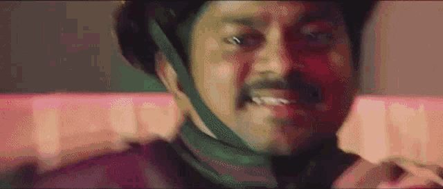 a man with a mustache is wearing a bicycle helmet and making a funny face .