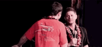 two men are standing next to each other on a stage and shaking hands .