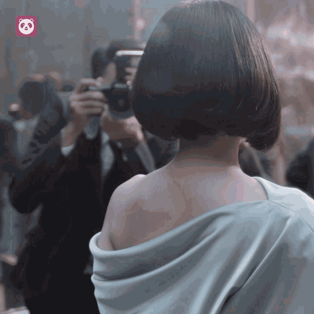 a man is taking a picture of a woman 's back with a panda logo in the corner