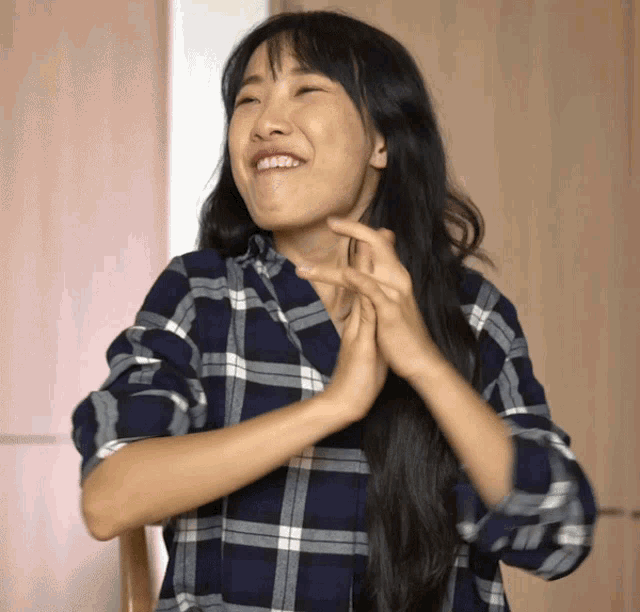 a woman wearing a plaid shirt is making a face