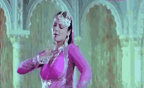 a woman in a pink dress is dancing in a room with her hands outstretched .
