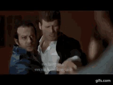 two men are standing next to each other in a room and one of them is pointing at the other .