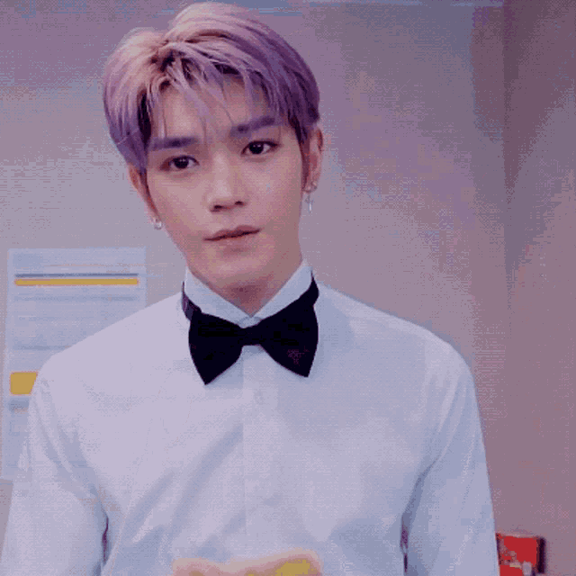 a man with purple hair is wearing a white shirt and a bow tie .