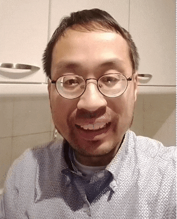 a man wearing glasses and a blue shirt is smiling for a picture .