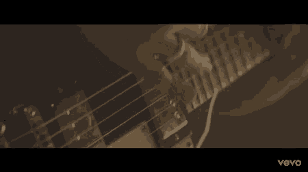 a close up of a man playing a guitar with the word vevo on the bottom right