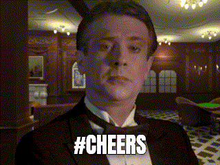 a man in a tuxedo says cheers in a room