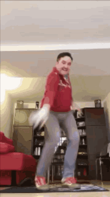 a man in a red shirt is jumping in the air while holding a wii controller