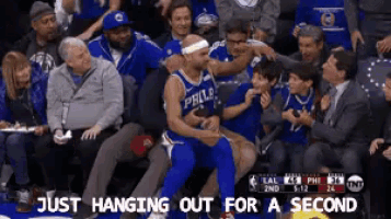 a philadelphia basketball player sits in the stands surrounded by fans