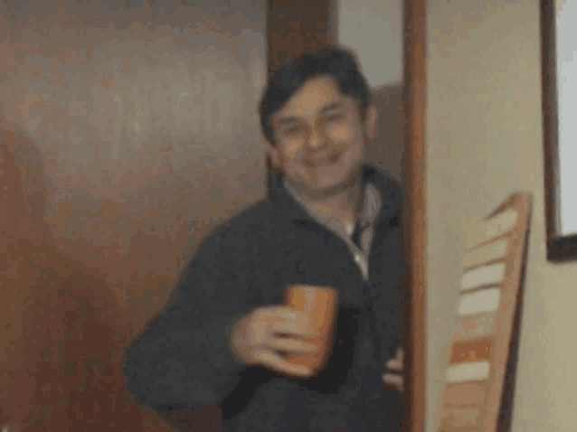 a man standing in a doorway holding a cup of coffee