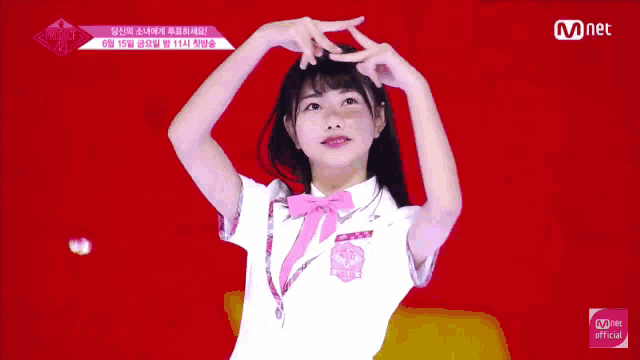 a girl in a white shirt with a pink bow and a mnet logo