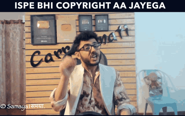 a man wearing glasses is sitting in front of a wooden wall with the words ispe bhi copyright aa jayega on it