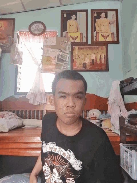 a man wearing a shirt that says ' ninja ' on it sits on a bed