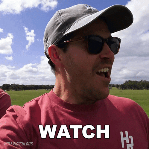 a man wearing sunglasses and a hat with the word watch on his shirt