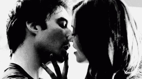 a man and a woman are kissing each other in a black and white photo .