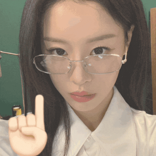 a woman wearing glasses and a white shirt is giving a middle finger