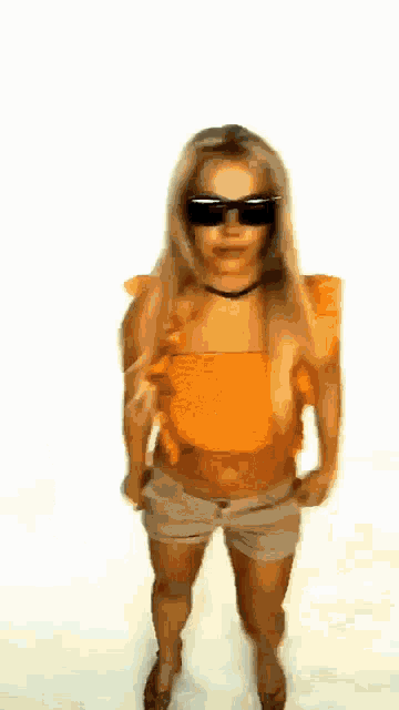 a woman wearing sunglasses and a yellow top is standing in front of a white background