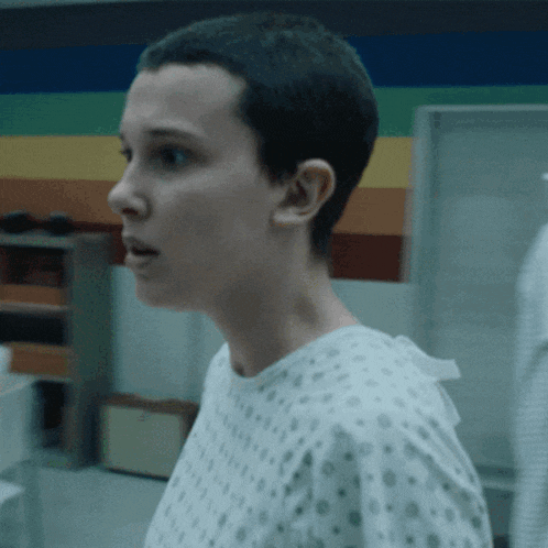 a woman in a hospital gown with a shaved head