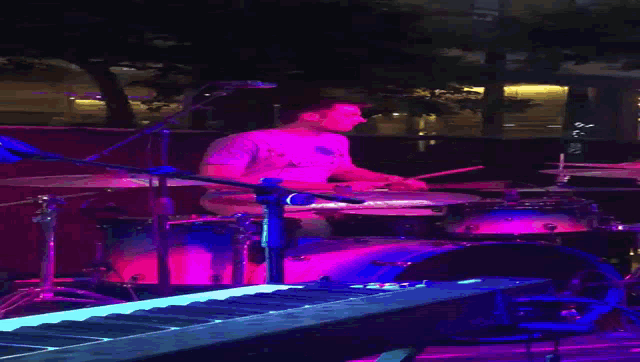 a man playing drums in front of a piano that says ' yamaha ' on it