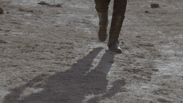 a person walking on a dirt road wearing a pair of brown boots