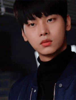 a close up of a young man wearing a black turtleneck and blue jacket