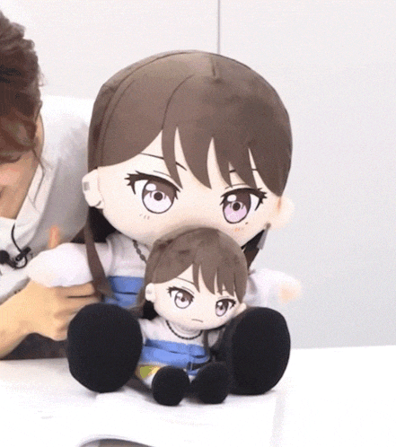 a woman is holding two stuffed dolls one of which is a girl with purple eyes