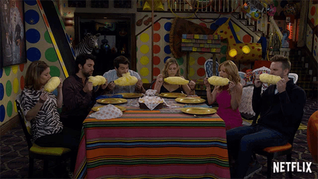a group of people sitting around a table eating cotton candy with a netflix logo on the bottom right