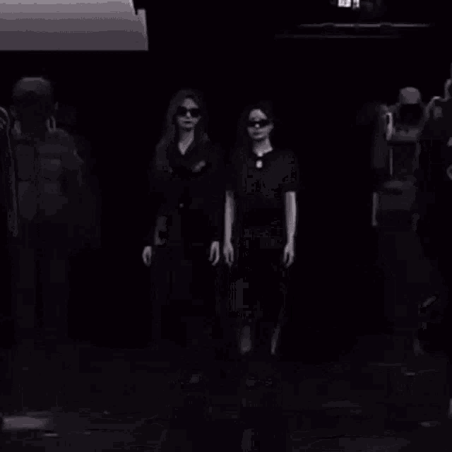 a group of people are walking down a runway at a fashion show in a black and white photo .