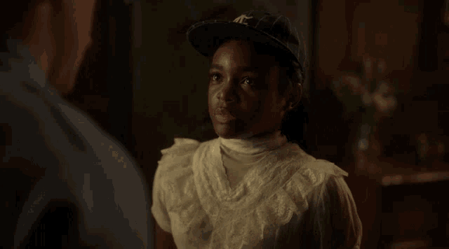 a young girl wearing a new york yankees baseball cap