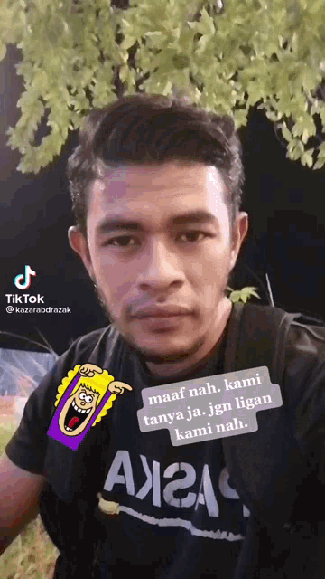 a man wearing a black shirt with a sticker on it that says maaf nah kami tanya ja jgn ligan kami nah